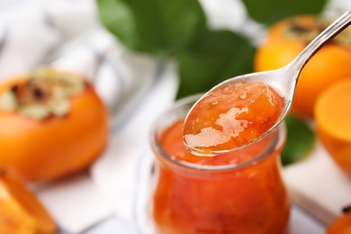 Photo of Spoon of tasty persimmon jam, closeup. Space for text