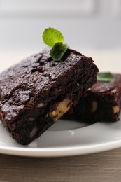 Delicious brownies with nuts and mint on wooden table, closeup