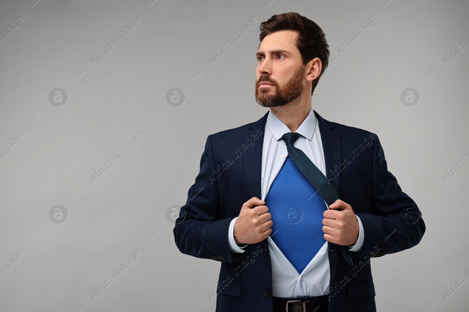 Photo of Confident businessman wearing superhero costume under suit on beige background. Space for text