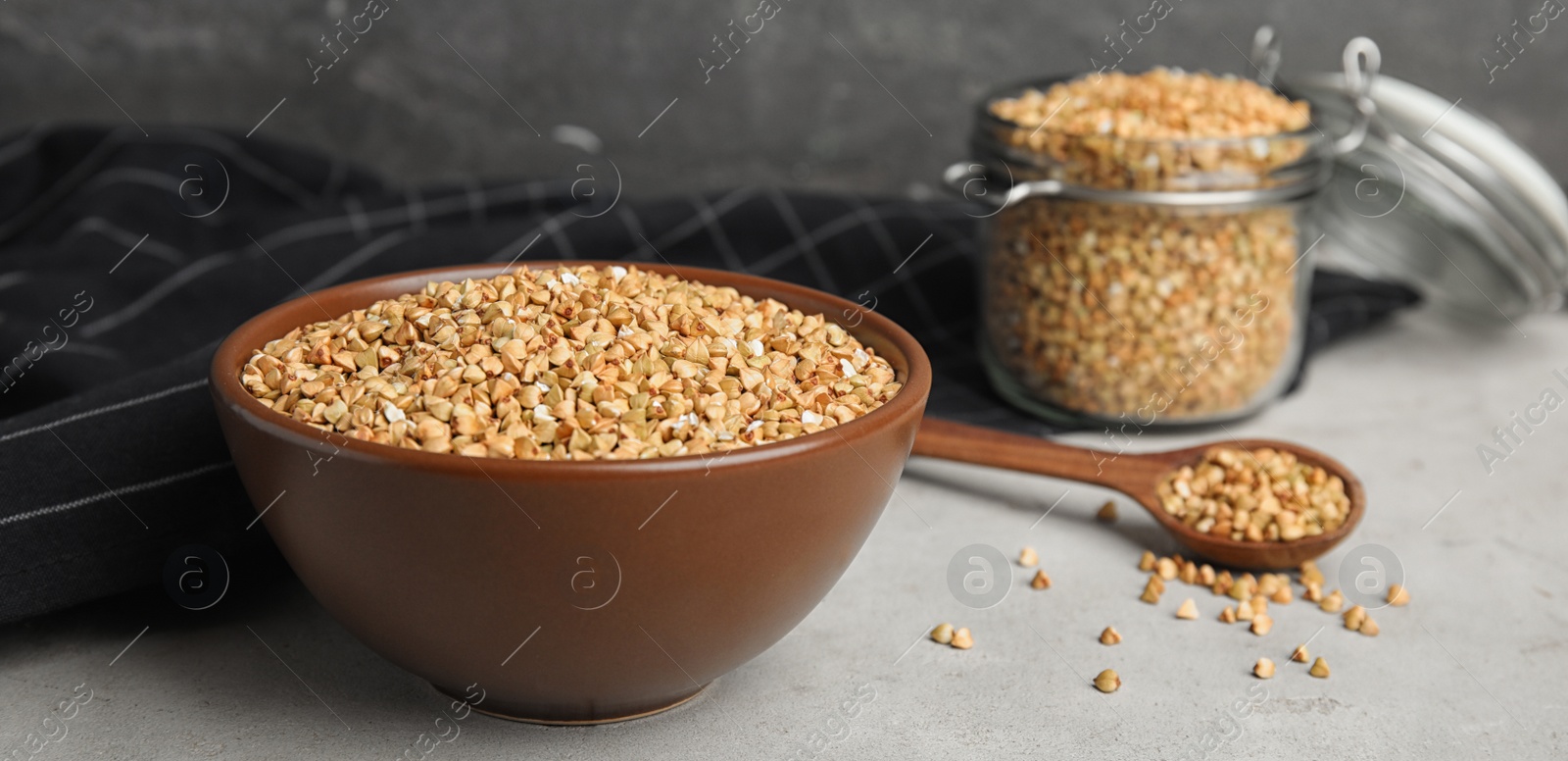 Image of Uncooked green buckwheat grains in bowl on table. Banner design