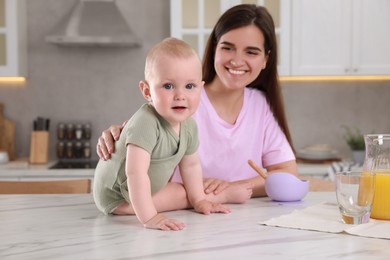 Photo of Happy young woman and her cute little baby cooking together in kitchen