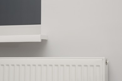 Photo of Modern panel radiator under window indoors. Heating system