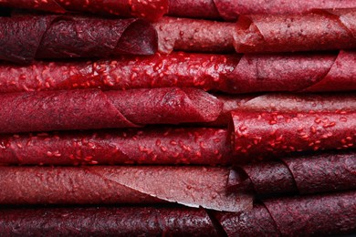 Photo of Delicious fruit leather rolls as background, top view