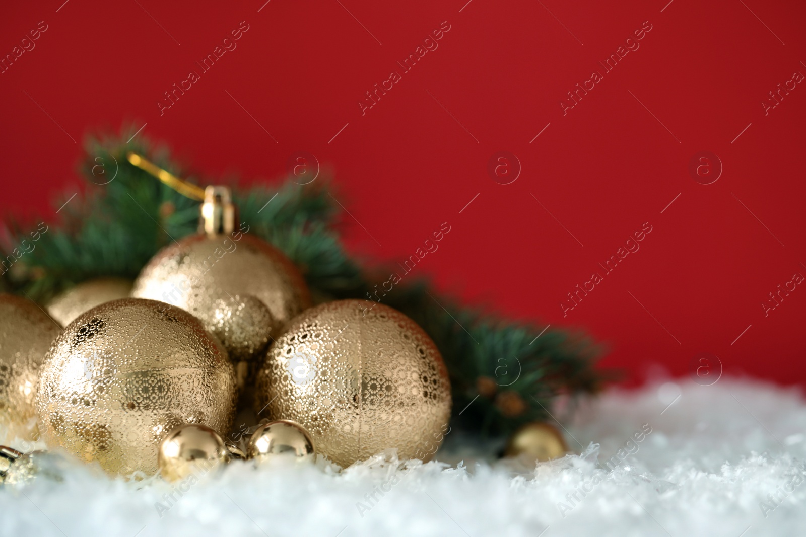 Photo of Beautiful Christmas balls on snow against red background. Space for text