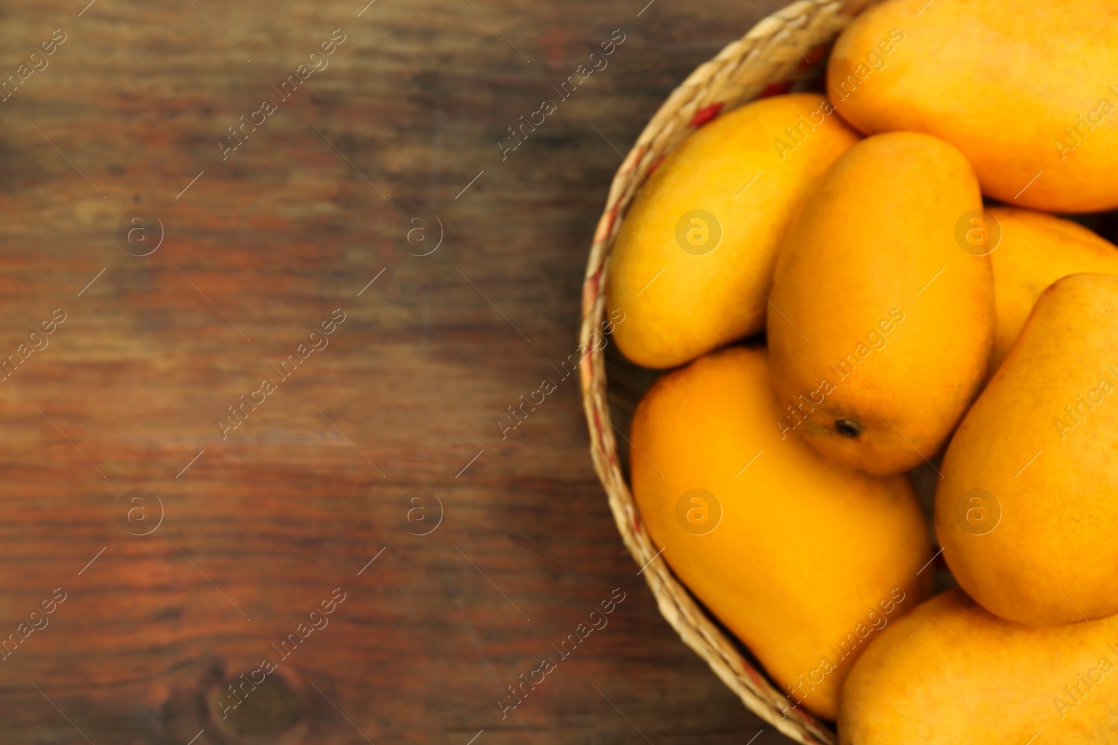 Photo of Delicious ripe juicy mangos on wooden table, top view. Space for text