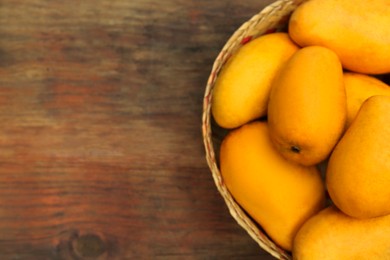 Delicious ripe juicy mangos on wooden table, top view. Space for text