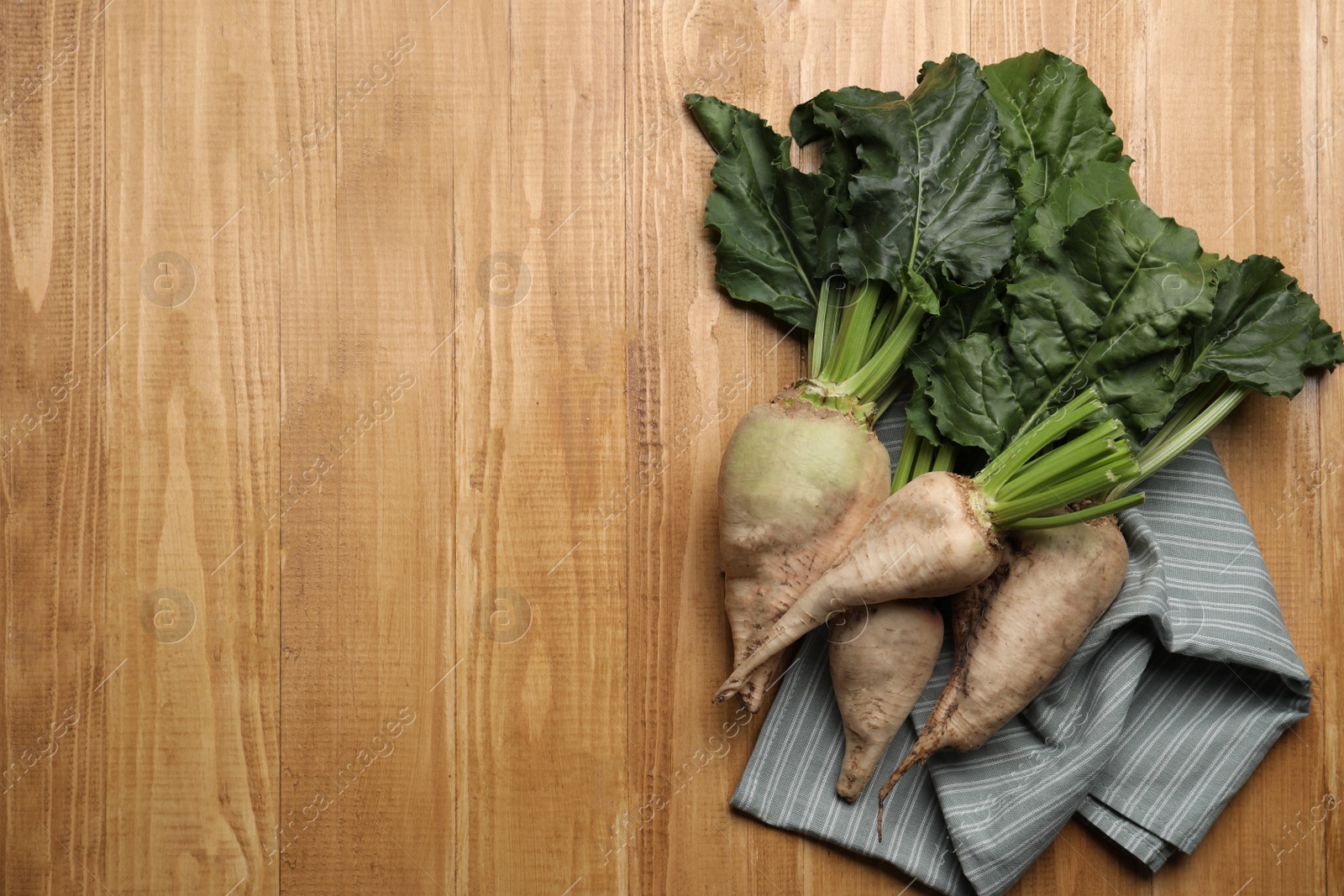 Photo of Fresh sugar beets with leaves on wooden table, flat lay. Space for text