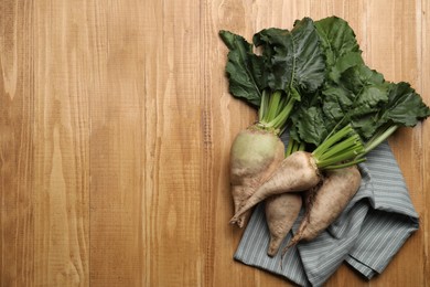 Photo of Fresh sugar beets with leaves on wooden table, flat lay. Space for text