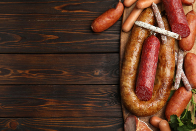 Photo of Different tasty sausages on wooden table, top view. Space for text