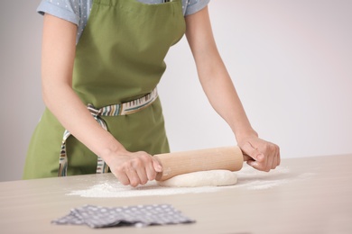 Photo of Woman rolling dough at table indoors, closeup