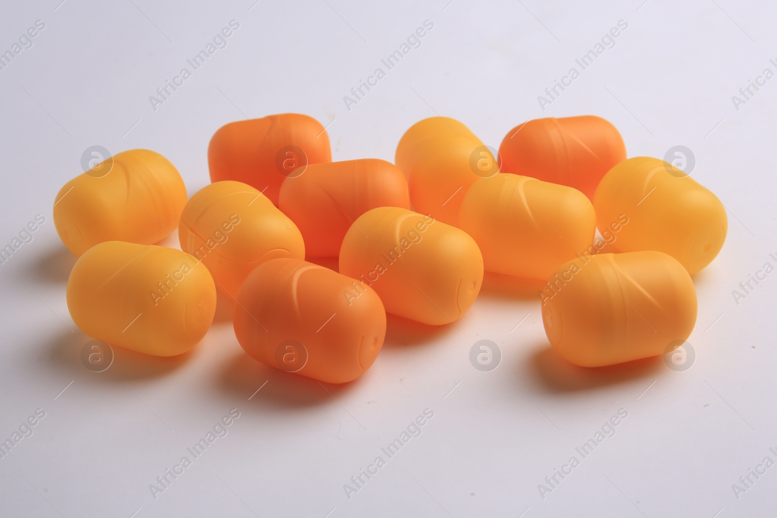 Photo of Sveti Vlas, Bulgaria - June 30, 2023: Orange plastic capsules from Kinder Surprise Eggs on white background, closeup