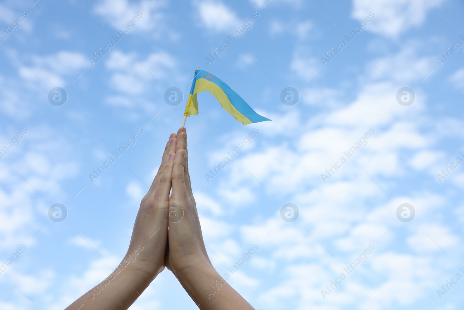 Photo of Woman holding national flag of Ukraine under blue sky with clouds, closeup. Space for text
