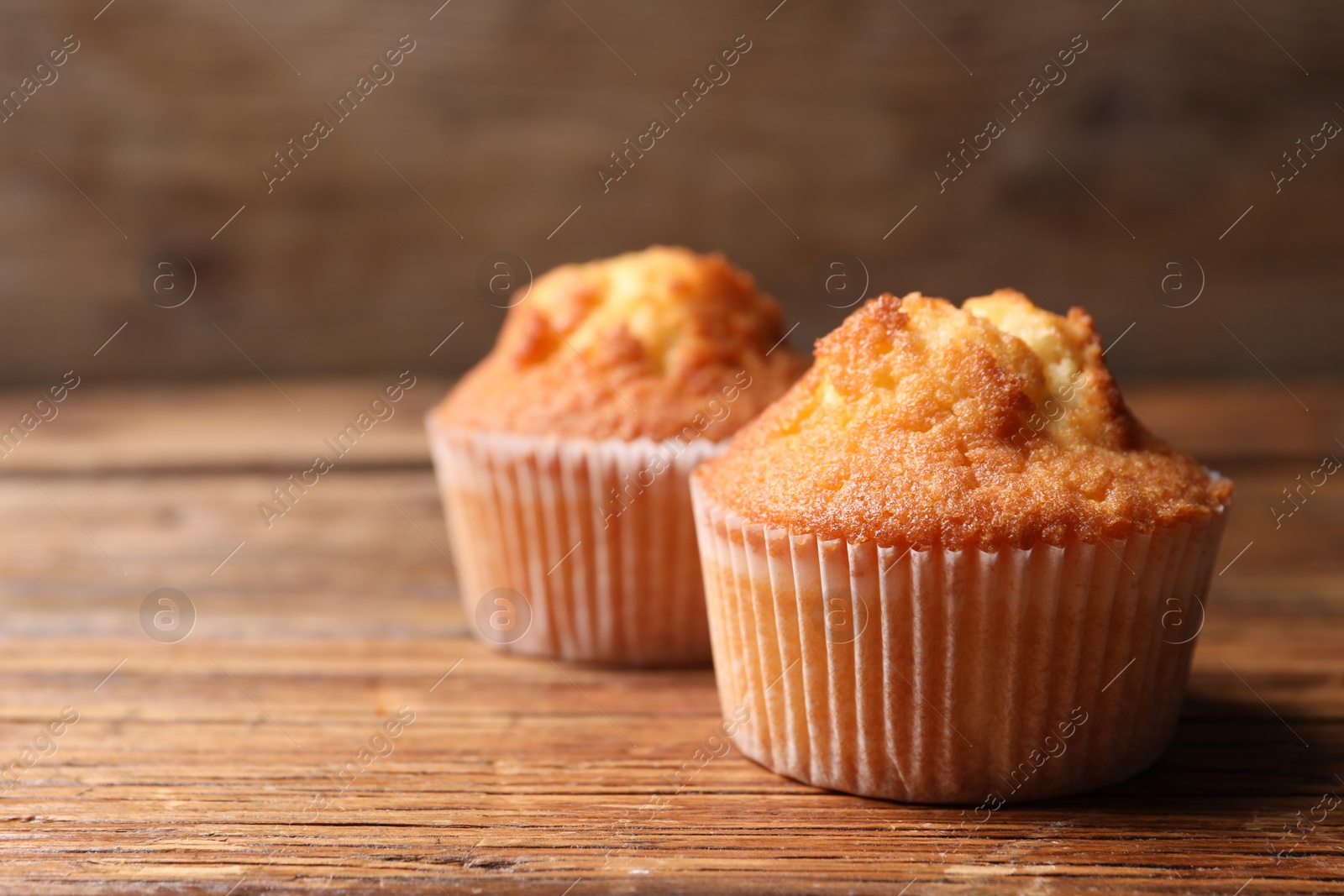 Photo of Delicious sweet muffins on wooden table, closeup. Space for text