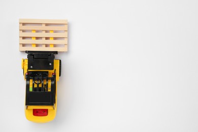 Photo of Toy forklift with wooden pallet on white background, top view