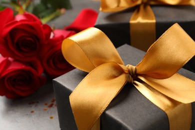 Black gift box and roses on grey table, closeup