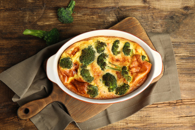 Photo of Tasty broccoli casserole in baking dish on wooden table, flat lay