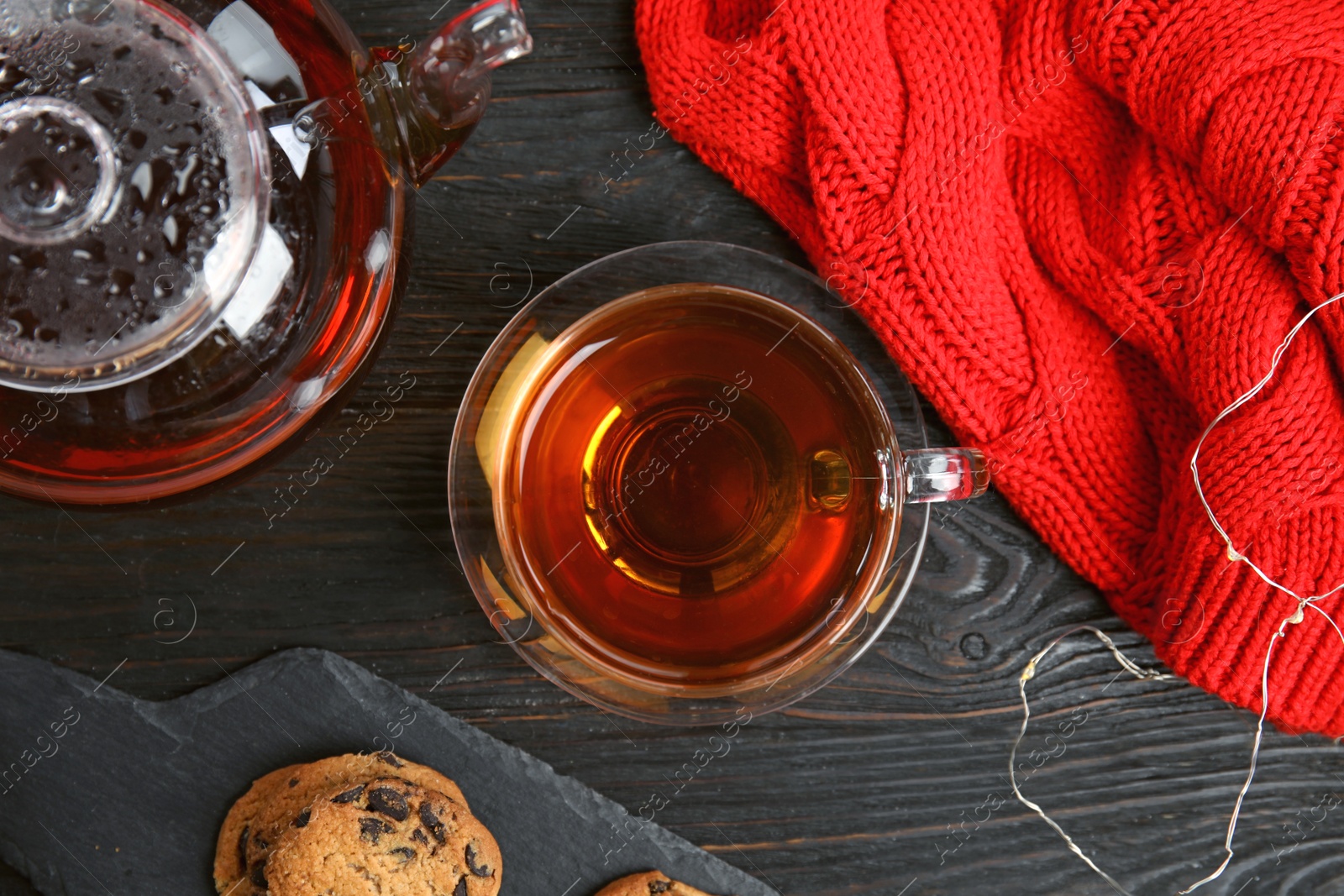 Photo of Flat lay composition with cup of hot tea on black wooden table. Winter drink