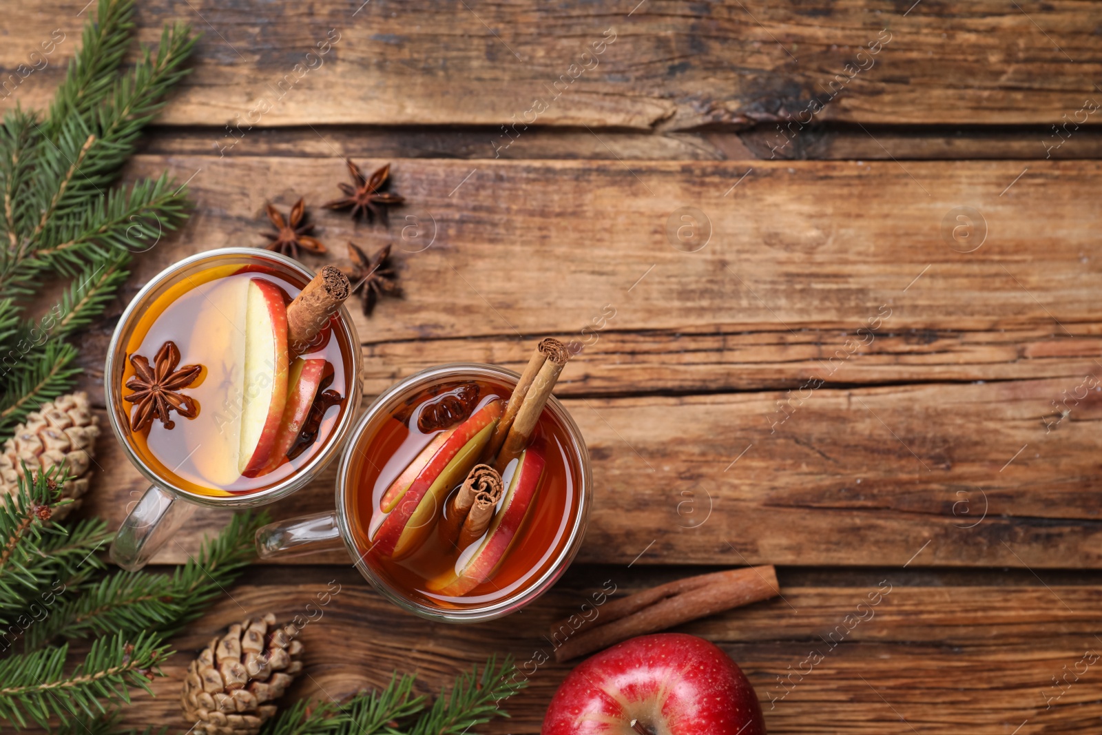 Photo of Hot mulled cider, ingredients and fir branches on wooden table, flat lay. Space for text