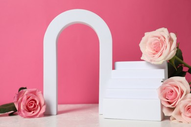 Stylish presentation for product. Geometric figures and beautiful roses on light table against pink background