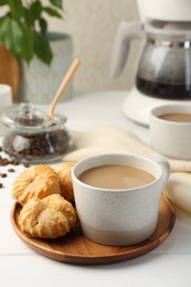 Photo of Aromatic coffee in cup and tasty profiteroles on white wooden table