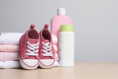 Photo of Baby clothes, shoes and accessories on wooden table. Space for text