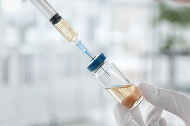 Photo of Doctor with syringe and medicine for vaccination on blurred background