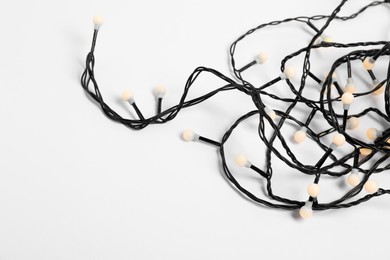 Photo of Tangled strings of Christmas lights on white background