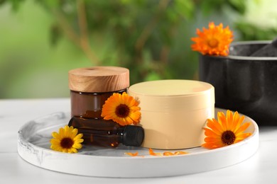 Photo of Different cosmetic products and beautiful calendula flowers on white table outdoors