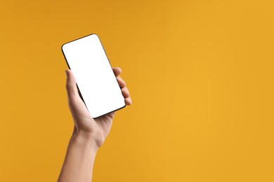 Photo of Man holding smartphone with blank screen on yellow background, closeup. Mockup for design
