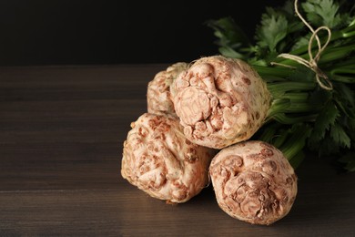 Photo of Fresh raw celery roots on wooden table, closeup. Space for text