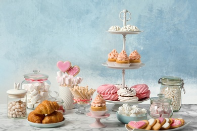 Photo of Candy bar with different sweets on white marble table against color background