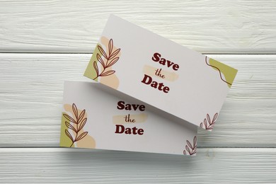 Photo of Beautiful cards with Save the Date phrase on white wooden background, top view