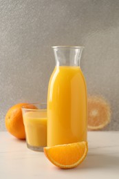 Tasty fresh oranges and juice on white marble table