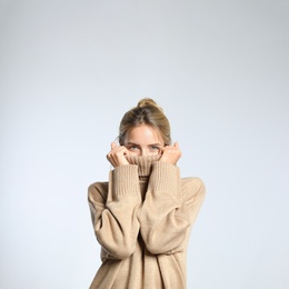 Photo of Beautiful young woman wearing knitted sweater on light grey background
