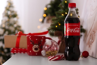 Photo of MYKOLAIV, UKRAINE - JANUARY 13, 2021: Bottle of Coca-Cola in room decorated for Christmas
