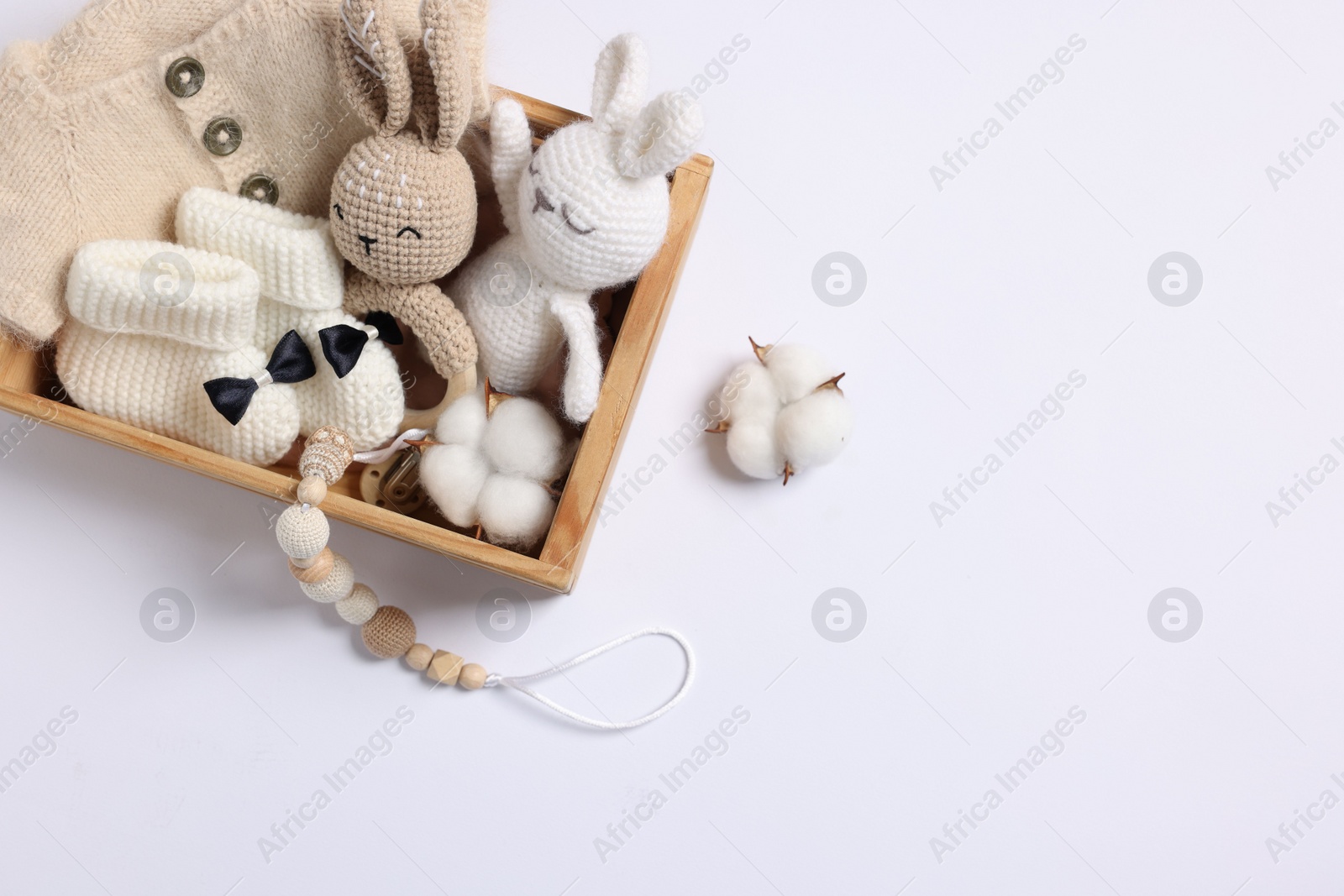 Photo of Different baby accessories and clothes in wooden crate on white background, top view. Space for text