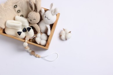 Photo of Different baby accessories and clothes in wooden crate on white background, top view. Space for text