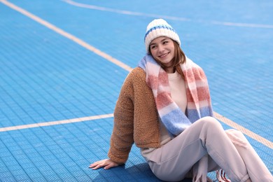Photo of Beautiful woman in warm scarf and hat outdoors, space for text