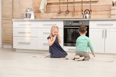 Photo of Cute children sitting near oven in kitchen