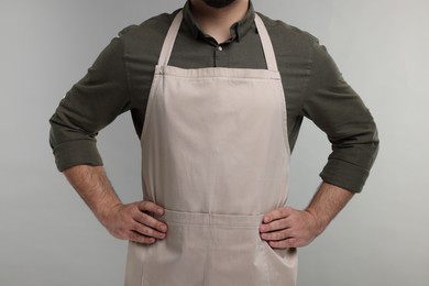 Photo of Man in kitchen apron on grey background, closeup. Mockup for design