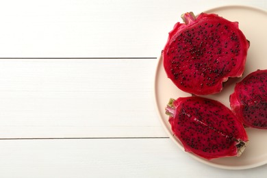 Photo of Plate with delicious cut red pitahaya fruit on white wooden table, top view. Space for text