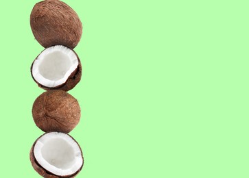 Image of Stack of fresh coconuts on pale light green background. Space for text