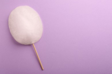 Photo of One sweet cotton candy on violet background, top view. Space for text