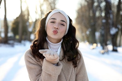 Photo of Portrait of beautiful woman blowing kiss in snowy park