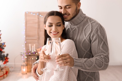 Photo of Happy young couple with glasses of champagne celebrating Christmas at home