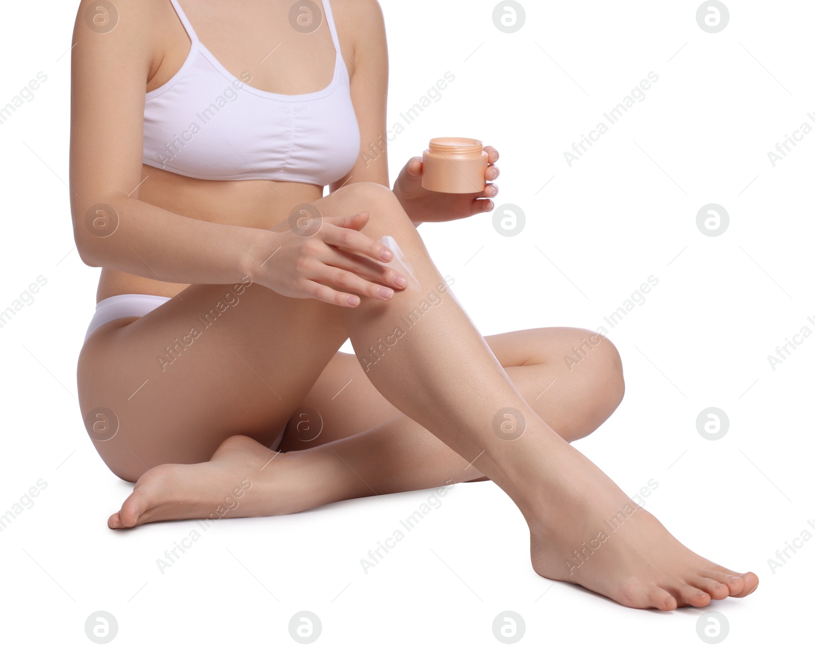 Photo of Young woman applying body cream onto leg on white background, closeup
