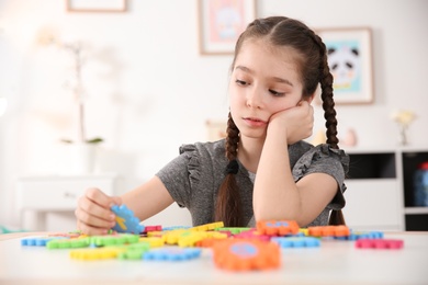 Photo of Little autistic girl playing with puzzles at home