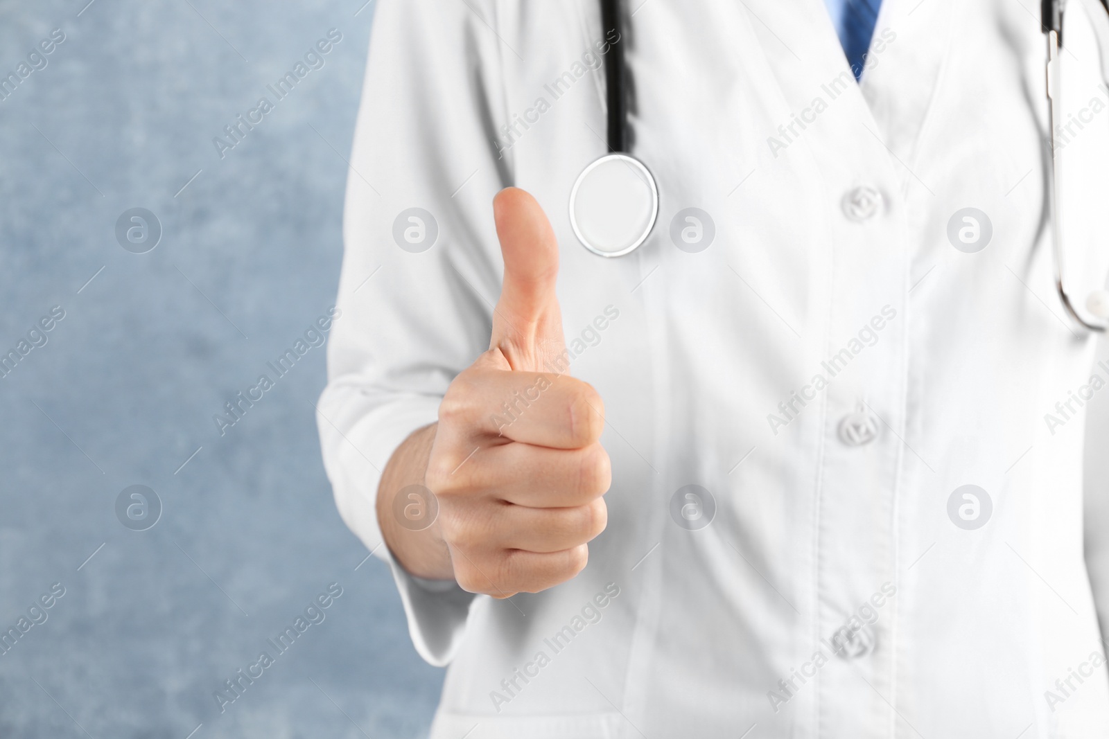 Doctor showing thumb up on blue background, closeup. Medical service Photo of Doctor showing thumb up on blue background, closeup. Medical service