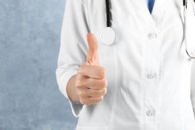 Photo of Doctor showing thumb up on blue background, closeup. Medical service