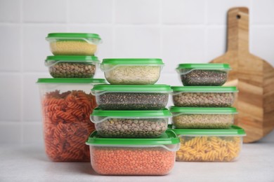 Photo of Plastic containers filled with food products on white table near tiled wall
